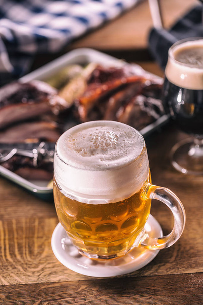 Glas licht bier in pub of restavurant op tafel met delicoius food - Foto, afbeelding