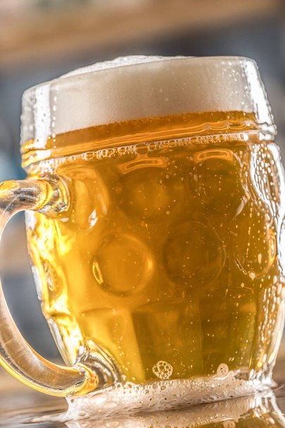Mug of cold beer on bar counter in pub or restaurant - Foto, afbeelding