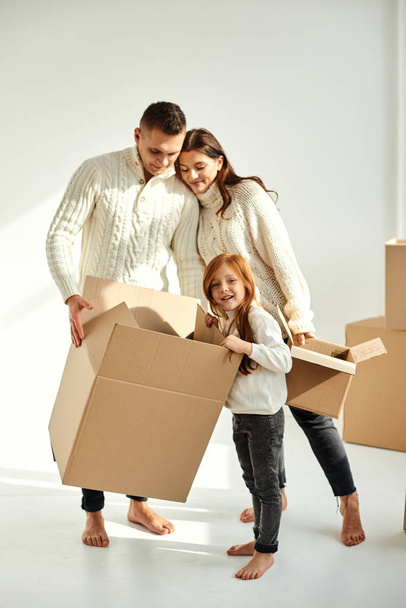 Familia desembalaje cajas de cartón en un nuevo hogar en un fondo blanco
 - Foto, imagen