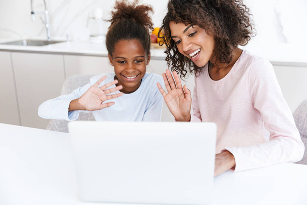 Image of african american woman and her daughter using laptop at - Foto, immagini
