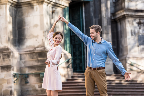 пара молодих, веселих туристів танцюють на вулиці під сонячним світлом
 - Фото, зображення