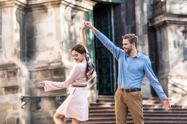 pareja de turistas jóvenes y elegantes bailando en la calle a la luz del sol
 - Foto, imagen