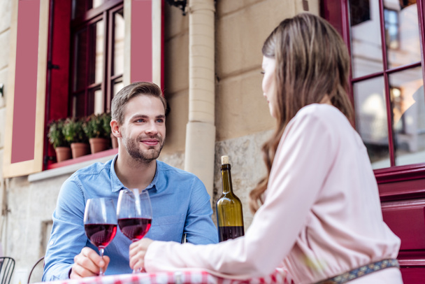 heureux jeune couple assis dans la rue café avec des verres de vin rouge
 - Photo, image