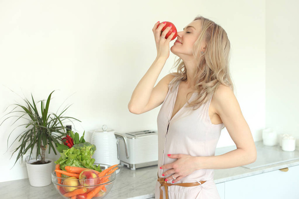Jovem sorrindo positivo mulher com legumes na cozinha
 - Foto, Imagem
