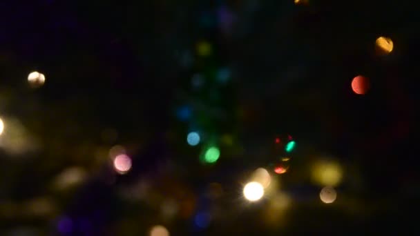 Heldere lichten bloemenslingers veelkleurig licht knipperen in het donker 's nachts Nieuwjaar op een feestelijke dennenboom met een speelgoed twinkelende dennennaalden op straat. Bokeh. - Video