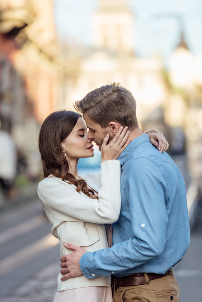 attractive young woman with closed eyes kissing handsome boyfriend on street - Foto, imagen