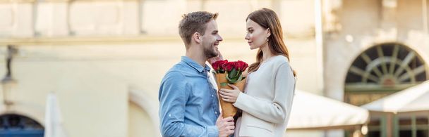 plan panoramique de bel homme présentant bouquet de roses à belle petite amie dans la rue
 - Photo, image