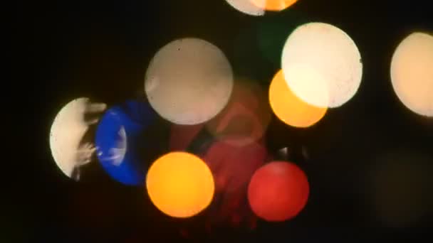 A lucfenyő ágain lévő tűk a szélben mozognak az új év ünnepi koszorúiból származó homályos és homályos színes fény hátterében. Bokeh!. - Felvétel, videó