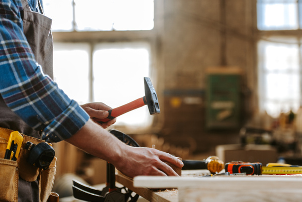 vista recortada del carpintero sosteniendo el martillo en taller
  - Foto, Imagen