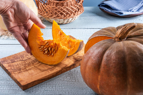 Taking freshly cut orange pumpkin slices by hand - Zdjęcie, obraz