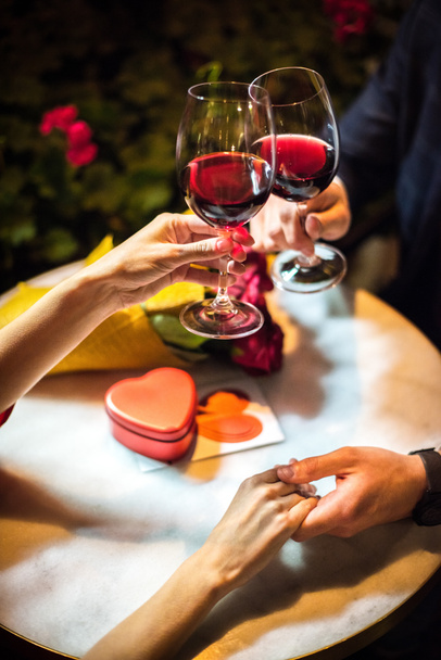 oříznutý pohled na muže cinkání sklenice červeného vína s přítelkyní při navrhování sňatku - Fotografie, Obrázek