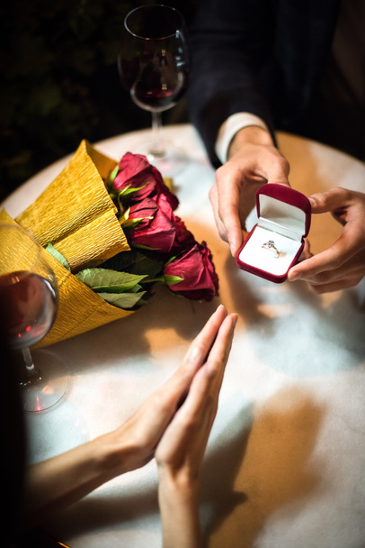 Evlenme teklifi ederken, bir erkeğin evlilik yüzüğünü kız arkadaşına sunması. - Fotoğraf, Görsel