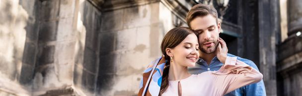 panoramic shot of happy couple hugging while standing on street - Foto, Bild