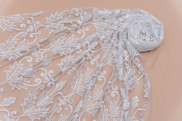 a background image of ivory-colored lace cloth. White lace on beige background. - Photo, Image