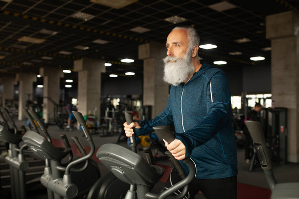 Bearded Senior Man On Running Machine In Gym. Treadmill.  - Фото, изображение