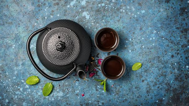 Tetera japonesa negra de hierro fundido con té y menta fresca
 - Foto, imagen