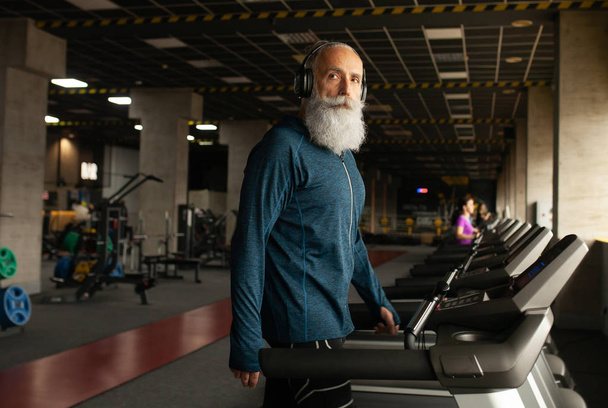 Bearded Senior Man On Running Machine In Gym. Treadmill.  - Фото, изображение