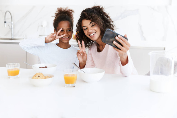 Imagen de la mujer americana y su hija usando el teléfono celular mientras h
 - Foto, imagen