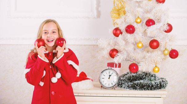 Favorite part decorating. Getting child involved decorating. Girl smiling face hold balls ornaments white interior background. How to decorate christmas tree with kid. Let kid decorate christmas tree - Foto, Bild