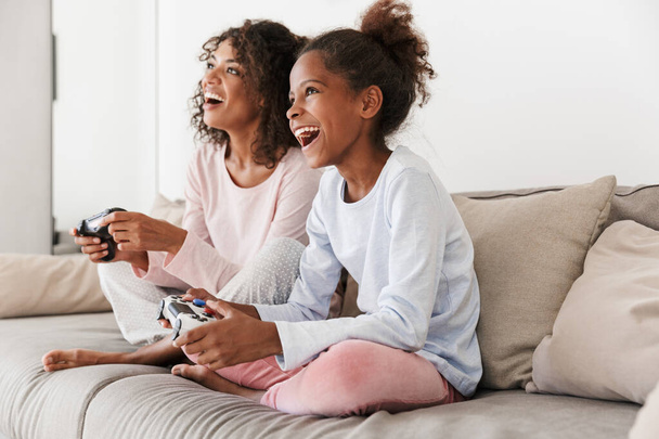 Image of american woman and little girl playing video games with - 写真・画像