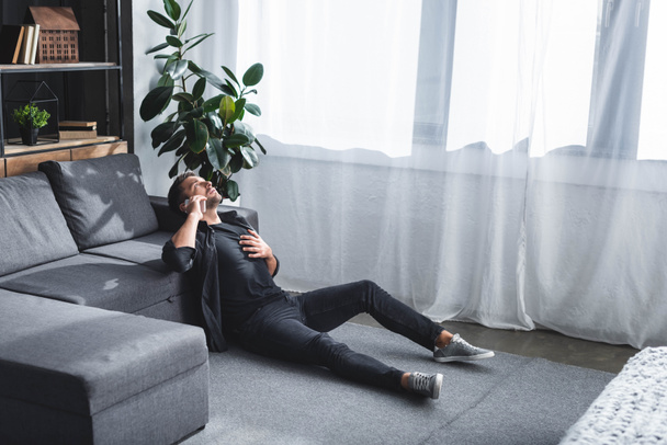 high angle view of handsome man having heart attack and talking on smartphone in apartment  - Fotoğraf, Görsel