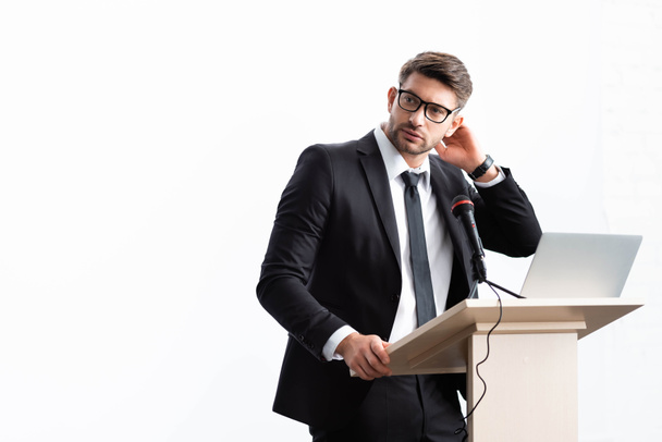 uomo d'affari in giacca e cravatta in piedi sul podio tribune e guardando lontano durante la conferenza isolato su bianco
 - Foto, immagini