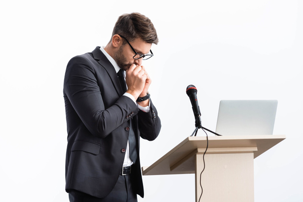 φοβισμένος επιχειρηματίας με κοστούμι στέκεται στο βάθρο tribune κατά τη διάρκεια συνεδρίου απομονώνονται σε λευκό  - Φωτογραφία, εικόνα