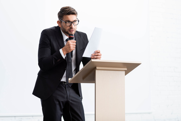 homme d'affaires effrayé en costume debout au podium tribune et parlant pendant la conférence isolé sur blanc
  - Photo, image