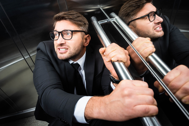 high angle view of scared businessman in suit with claustrophobia in elevator - 写真・画像