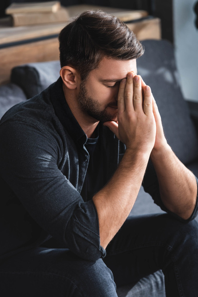 sad man with closed eyes obscuring face in apartment  - Photo, Image