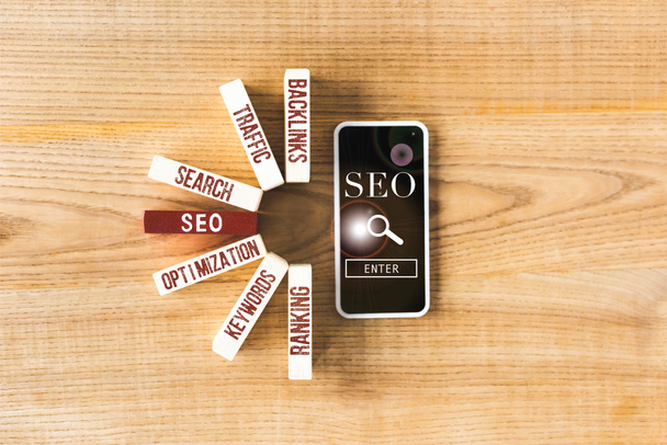 top view of wooden rectangles with concept words of seo and smartphone with seo illustration  - Photo, Image