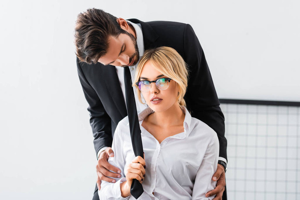 Sexy businesswoman pulling tie of businessman in office - Photo, Image