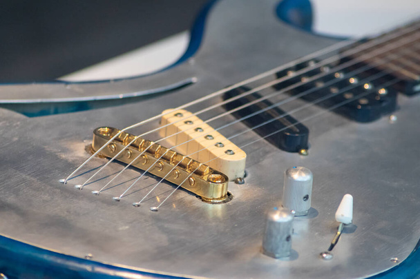 Η ηλεκτρική κιθάρα ως closeup αντιπροσωπεύει ροκ μπάντα, ηλεκτρικό ήχο κιθάρας, ηλεκτροφόρα συστήματα ήχου, hard rock καθώς και heavy metal ήχους και metal μπάντες - Φωτογραφία, εικόνα