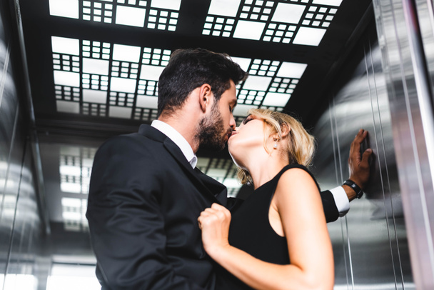 Businessman kissing colleague in office elevator - Foto, afbeelding