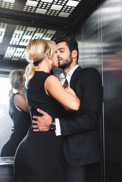 Business couple undressing while kissing in office elevator - Photo, Image