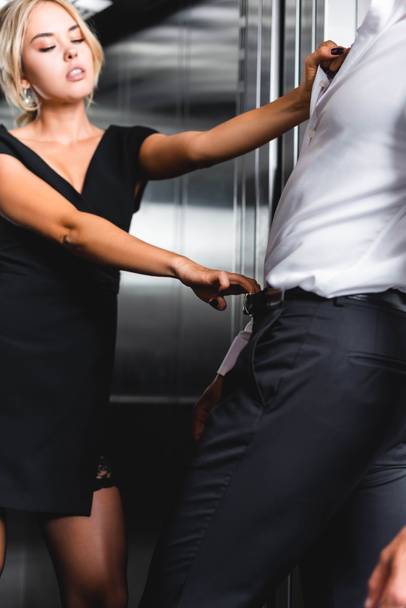 Vrouw trekken door middel van tailleband en shirt man in office lift - Foto, afbeelding