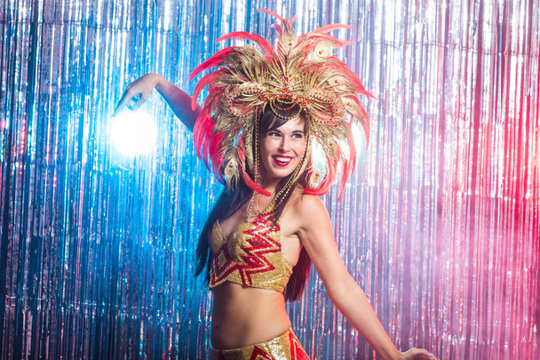 Carnaval, danser en vakantie concept-Beauty brunette vrouw in cabaret pak en hoofdtooi met natuurlijke veren en strass. - Foto, afbeelding