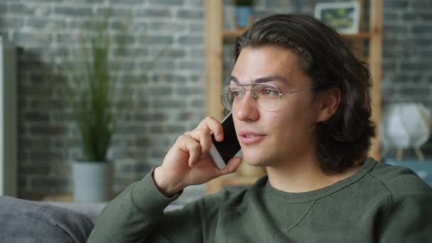 Joyful student talking on mobile phone in apartment enjoying conversation - Filmmaterial, Video