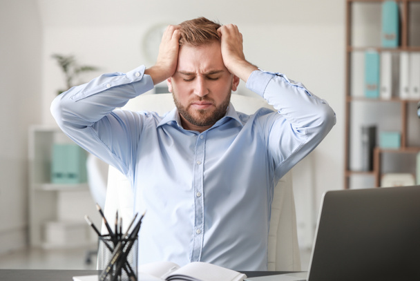 Young man suffering from headache in office - Zdjęcie, obraz