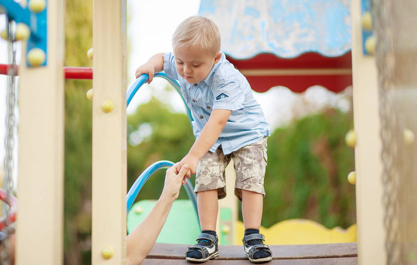 The daily life of a child with disabilities. A boy with Down Syndrome is playing in the playground. Chromosomal and genetic disorder in the baby. - Photo, image