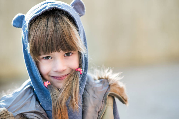 Portrait of happy child girl in warm clothes in autumn outdoors. - Photo, Image