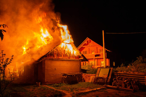 Casa de madera o granero ardiendo en llamas por la noche
. - Foto, Imagen