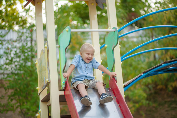 Engelli bir çocuğun günlük hayatı. Down Sendromlu bir çocuk oyun alanında oynuyor. Kromozom ve genetik bozukluk.. - Fotoğraf, Görsel