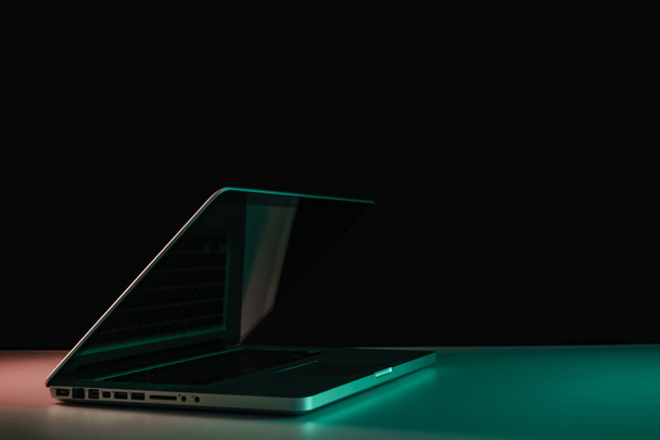 Beautiful silver laptop in the color light on a table and night background. - 写真・画像