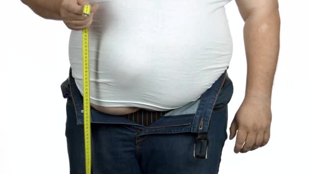 Lihava mies mittaa vatsaansa mittarin avulla.
. - Materiaali, video