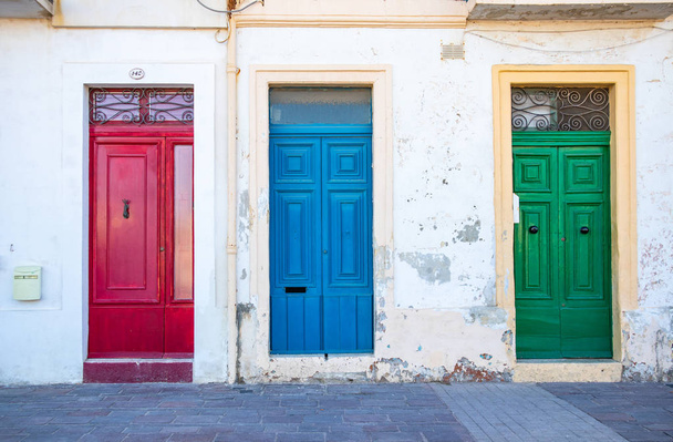 Trzy typowe maltańskie drzwi w wiosce Marsaxlokk. Czerwone, niebieskie, zielone drzwi. Malta - Zdjęcie, obraz