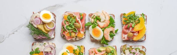 панорамний знімок свіжих і смачних бутербродів на білій мармуровій поверхні
  - Фото, зображення
