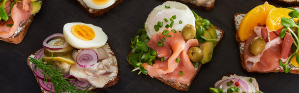 panoramic shot of rye bread with prepared danish smorrebrod sandwiches on grey surface  - Fotó, kép