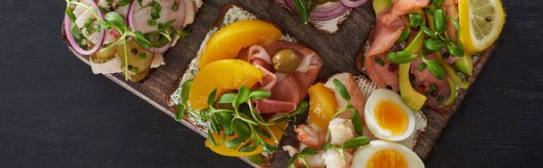 灰色の表面に新鮮なデンマーク産の細切りのサンドイッチとまな板のパノラマショット  - 写真・画像