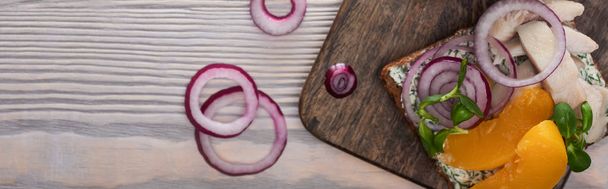 panoramic shot of rye bread with tasty smorrebrod sandwich on wooden surface  - Photo, Image